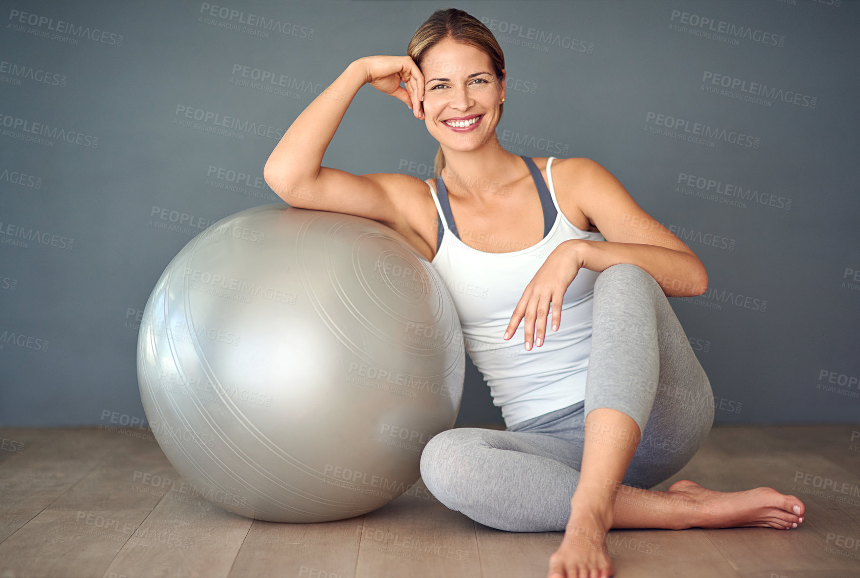 Buy stock photo Woman, exercise ball and training for portrait, wellness and fitness with smile for motivation. Gym, performance and athlete with wall background for workout health, weight loss support and pilates