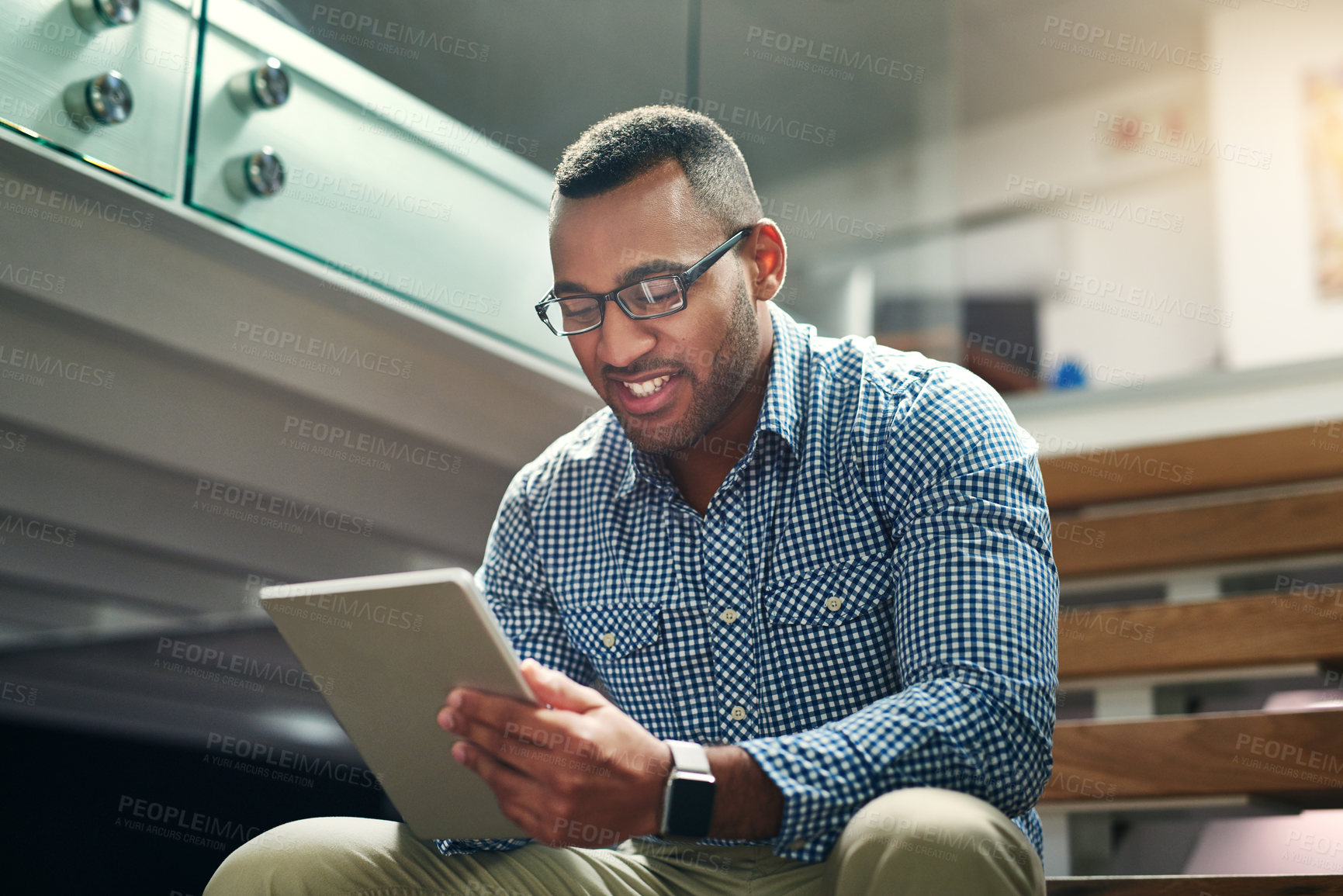Buy stock photo Cropped shot of a handsome young businessman using his tablet in the office