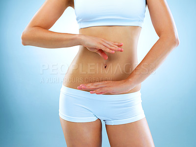 Buy stock photo Woman, stomach and body with blue background with hands for diet and exercise for health. Model, fitness and women in studio for digestion diet and workout with weight loss for healthy living.

