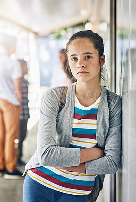 Buy stock photo Portrait of a lonely schoolgirl standing outside her classroom with classmates in the background