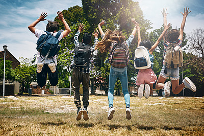 Buy stock photo Rearview shot of a group of unidentifiable schoolchildren jumping in the park