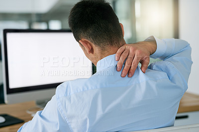 Buy stock photo Rearview shot of a young businessman holding his neck while sitting at his desk