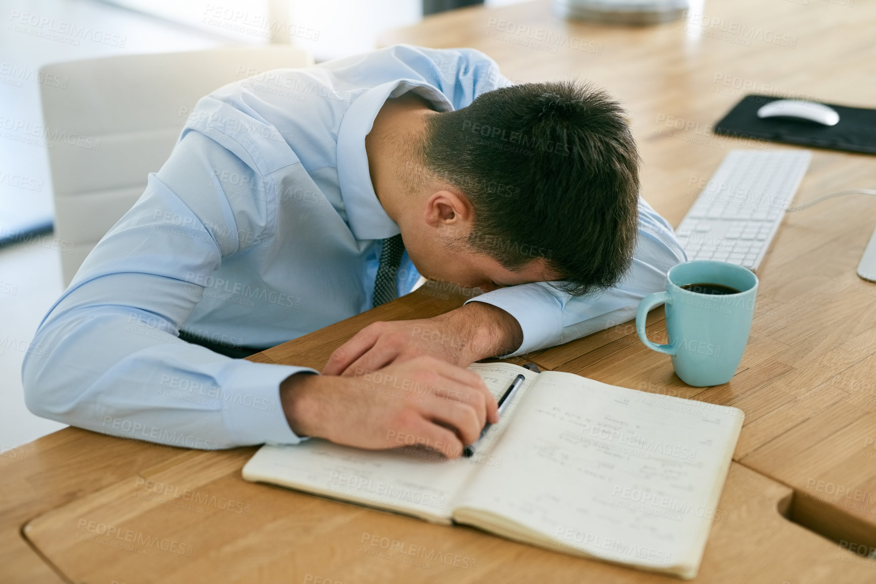 Buy stock photo High angle shot of a young, overworked businessman sleeping at his desk