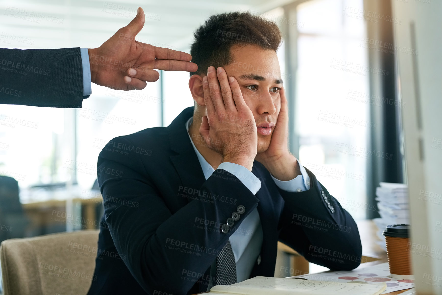 Buy stock photo Shot of a young businessman working while his boss gestures a finger gun to his head