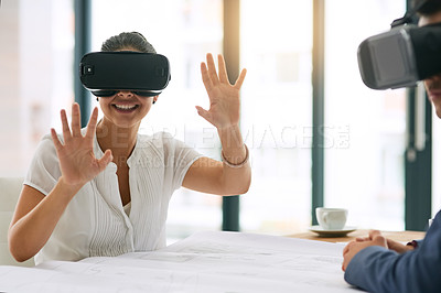 Buy stock photo Shot of a young businesswoman wearing a VR headset while working with a colleague in an office