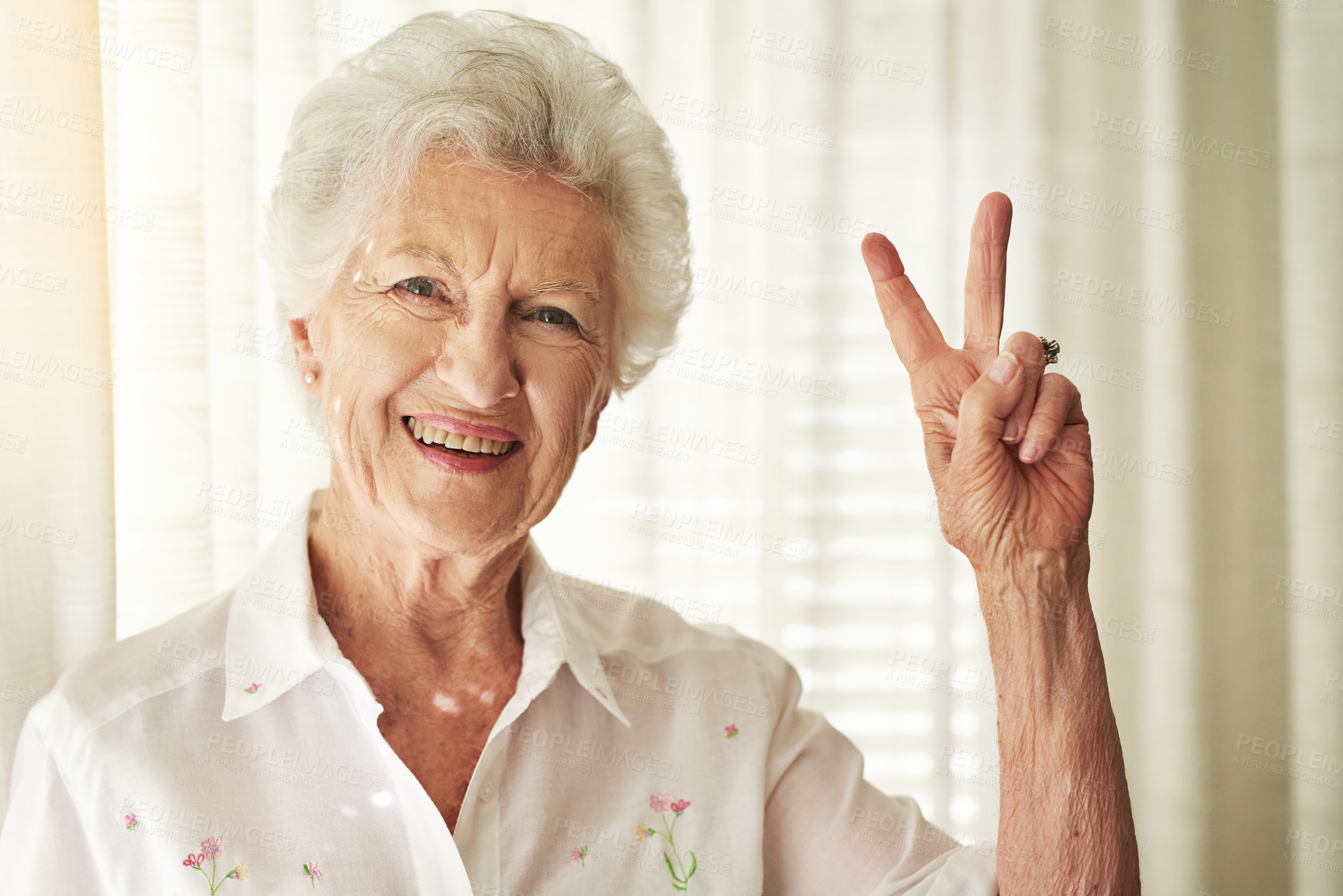 Buy stock photo Portrait of a happy elderly woman showing a peace gesture at home