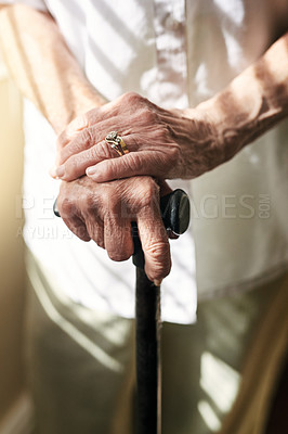 Buy stock photo Hands, walking stick and closeup with elderly woman, injury and mobility with balance in retirement in house. Cane, senior lady and person with disability, support or recovery in home with lens flare