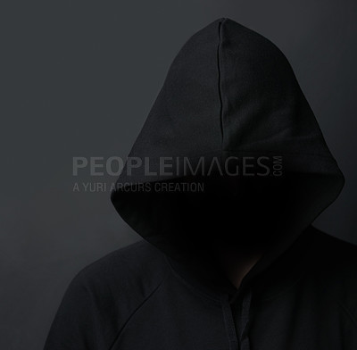 Buy stock photo Shot of an unidentifiable hooded man posing against a dark background