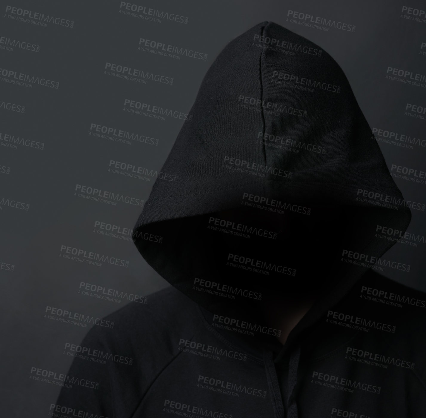 Buy stock photo Shot of an unidentifiable hooded man posing against a dark background