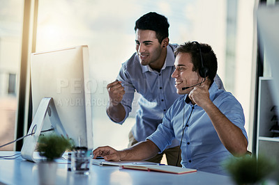 Buy stock photo Cropped shot of two call centre agents doing a fist pump while working together in an office