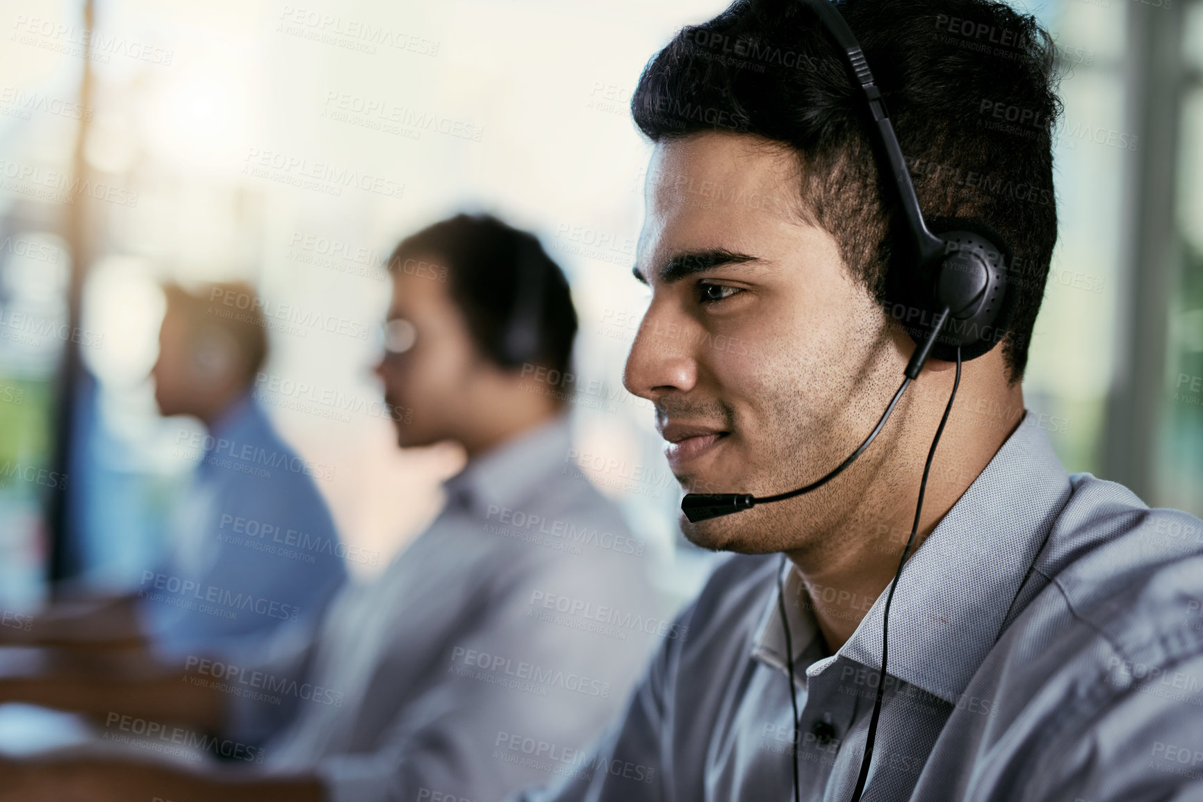 Buy stock photo Cropped shot of a call centre agent working in an office with his colleagues in the background