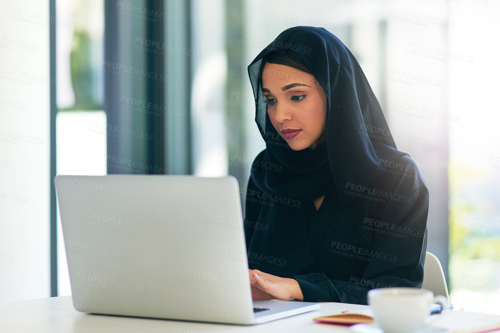 Buy stock photo Woman, muslim and laptop for career is working at the office on the internet for dubai and technology. Professional, computer and arabic with a hijab is on the web to design at a company with tech.