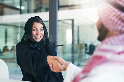 Buy stock photo Shot of a young muslim businesswoman shaking hands with an associate in a modern office