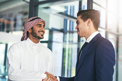 Buy stock photo Shot of a young muslim businessman shaking hands with an associate in a modern office