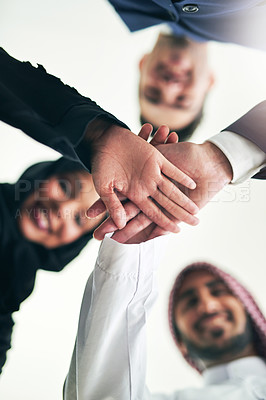 Buy stock photo Cropped shot of a team of colleagues joining hands in solidarity in an arabic office