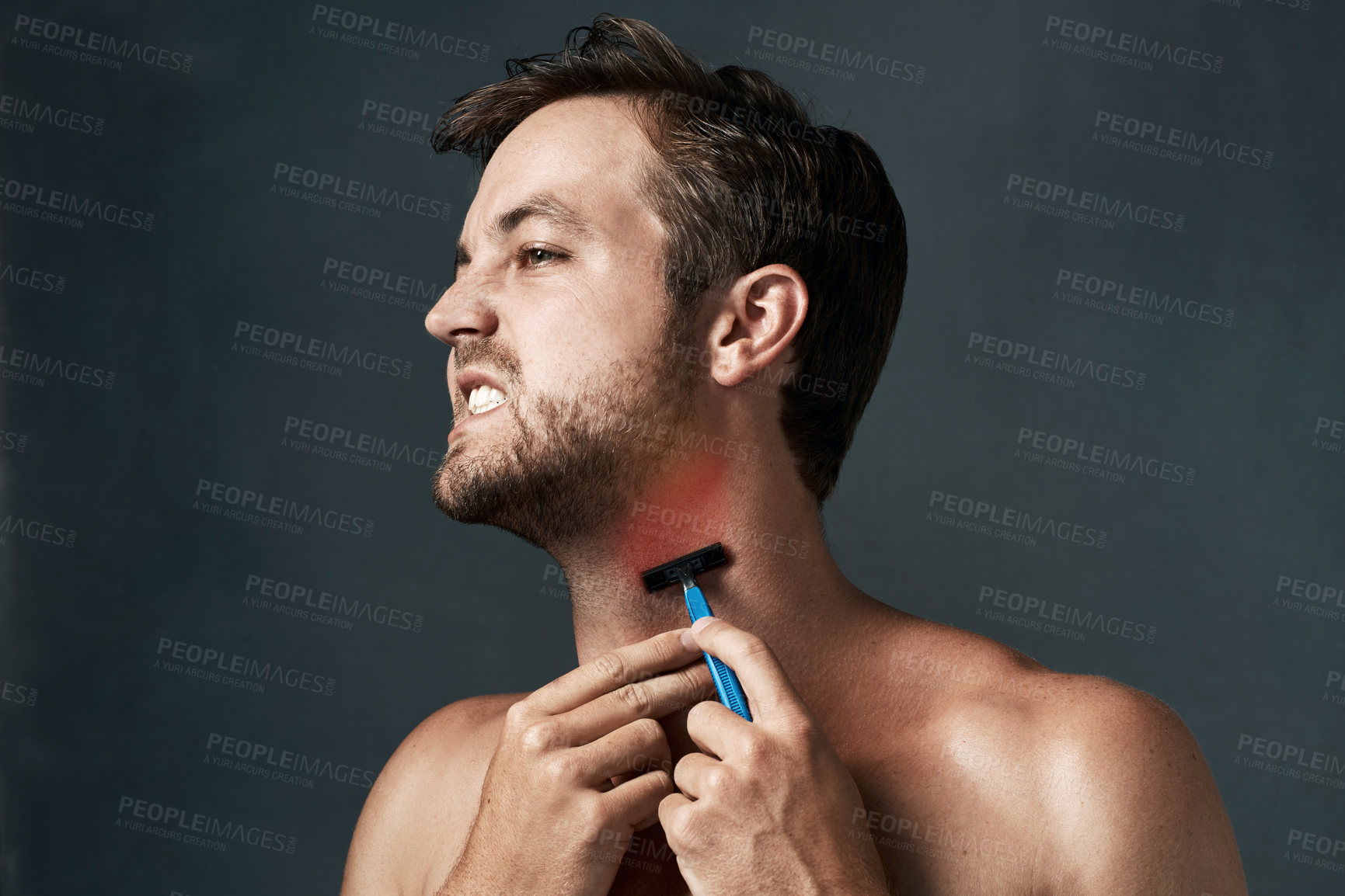 Buy stock photo Cropped shot of a handsome young man grimacing while shaving