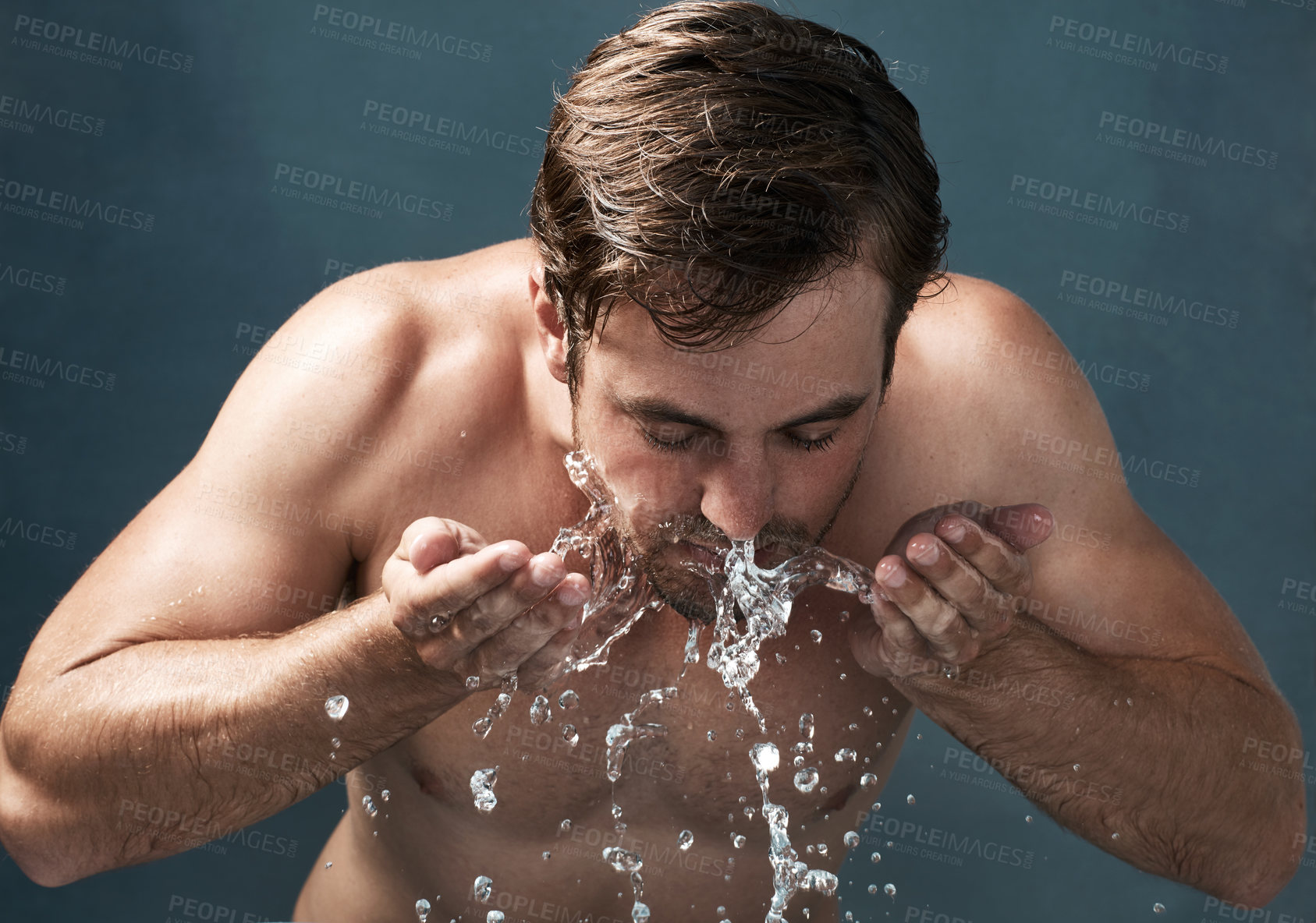 Buy stock photo Hygiene, man and skincare with water splash on face in studio background for cleaning, fresh and grooming. Male person, cosmetics and shirtless isolated on backdrop for wellness and dermatology