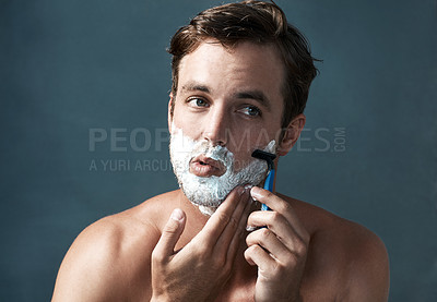 Buy stock photo Cropped shot of a handsome young man shaving against a grey background