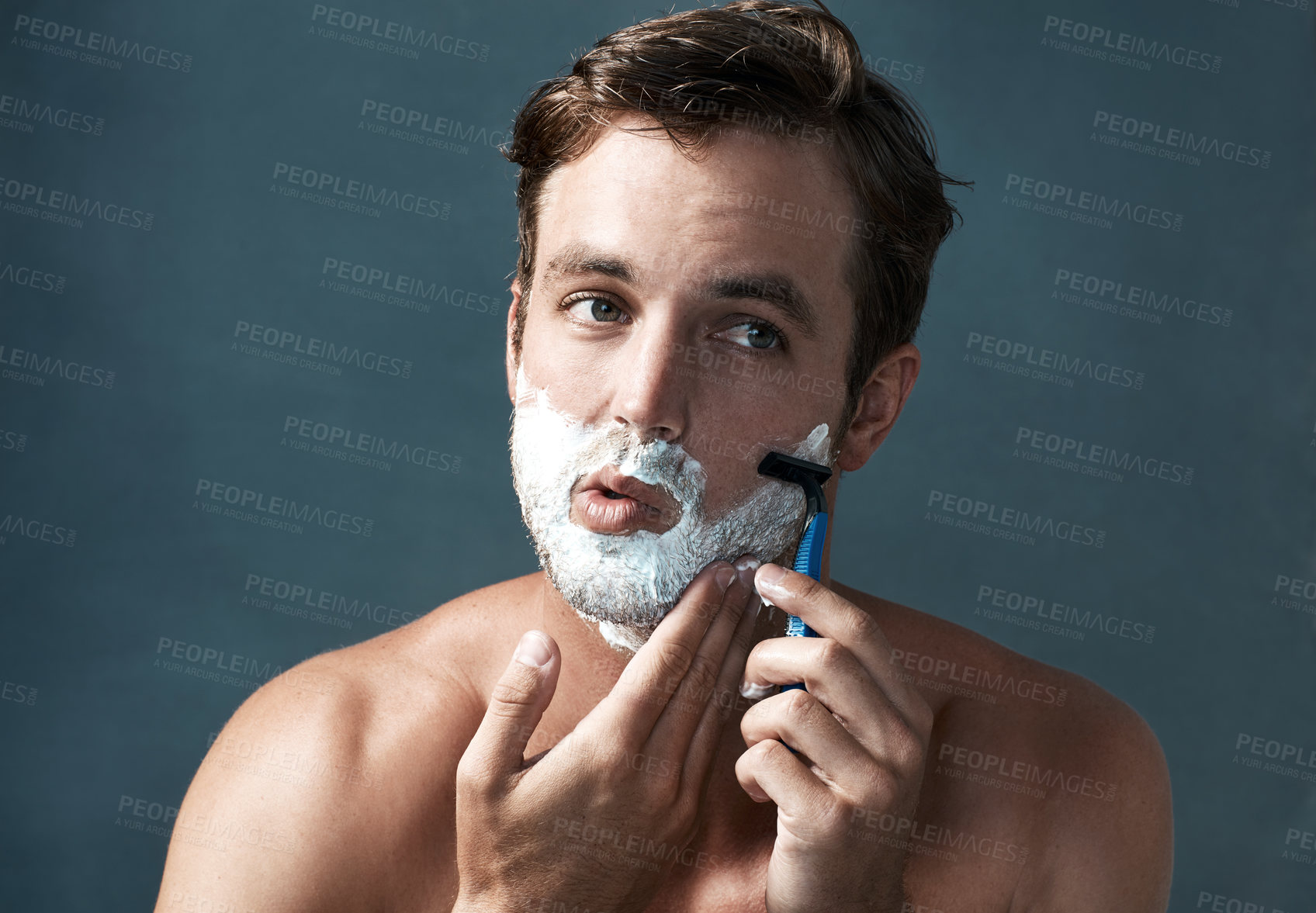Buy stock photo Cropped shot of a handsome young man shaving against a grey background