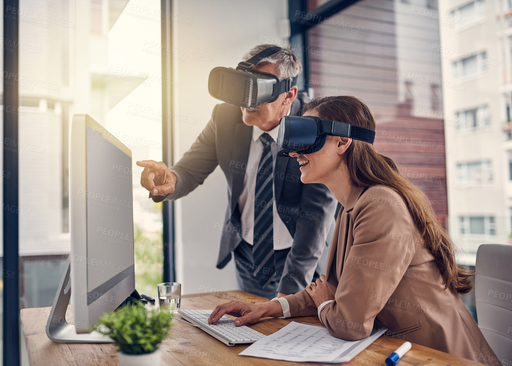 Buy stock photo Shot of two businesspeople wearing VR headsets while working on a computer in an office