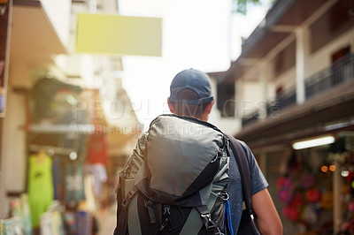 Buy stock photo Rearview shot of a young tourist wearing a backpack walking down a city street