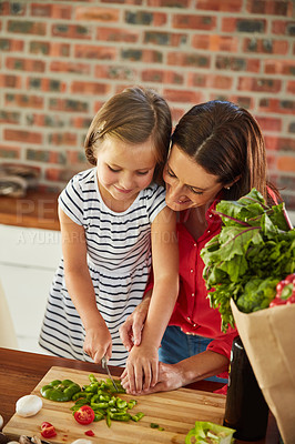 Buy stock photo Shot of a cute little girl chopping vegetables in the kitchen with her mother