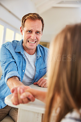 Buy stock photo Shot of a smiling father and his little daughter arm wrestling together at home