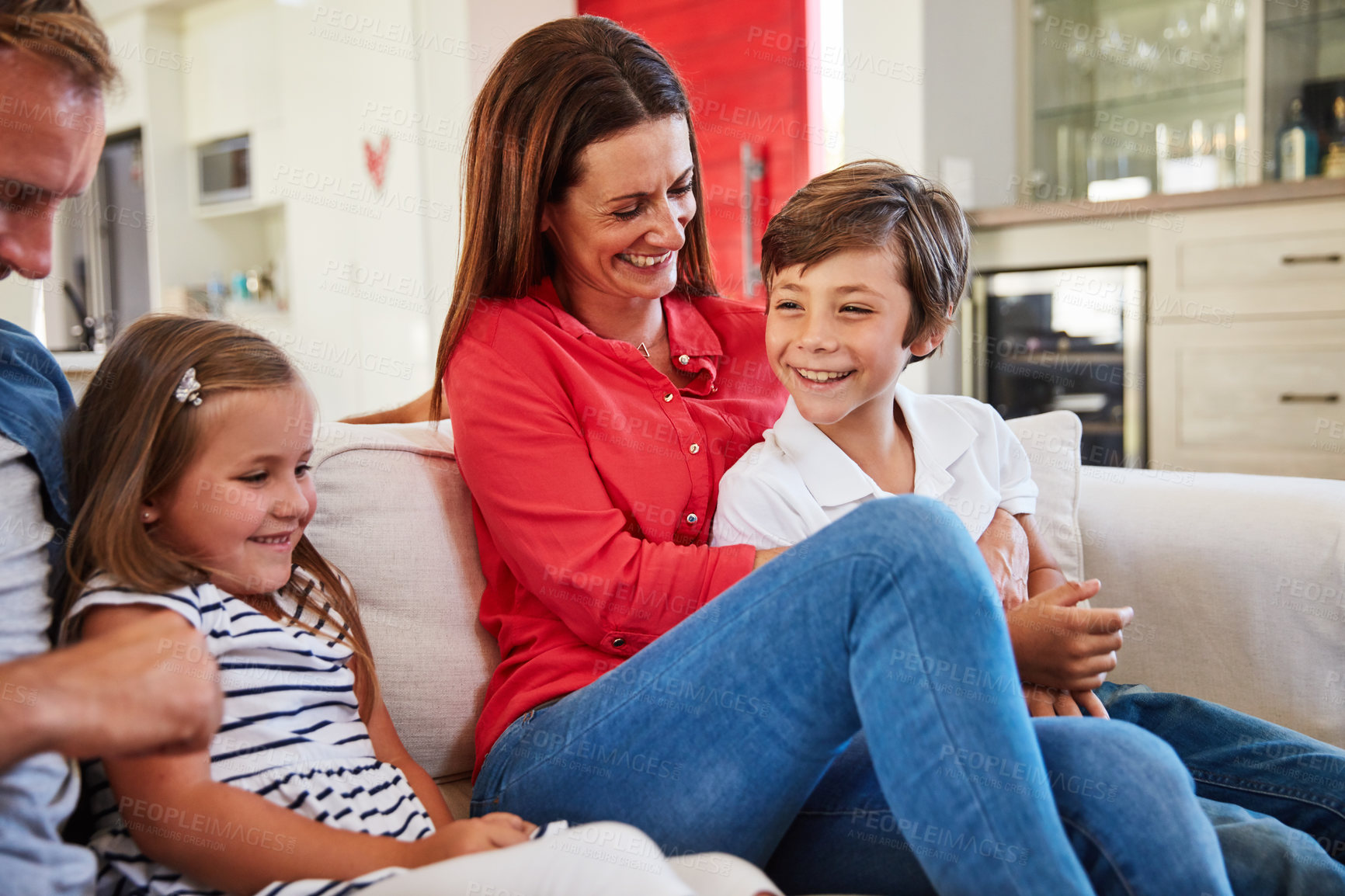 Buy stock photo Shot of smiling parents sitting with their young son and daughter on their living room sofa at home