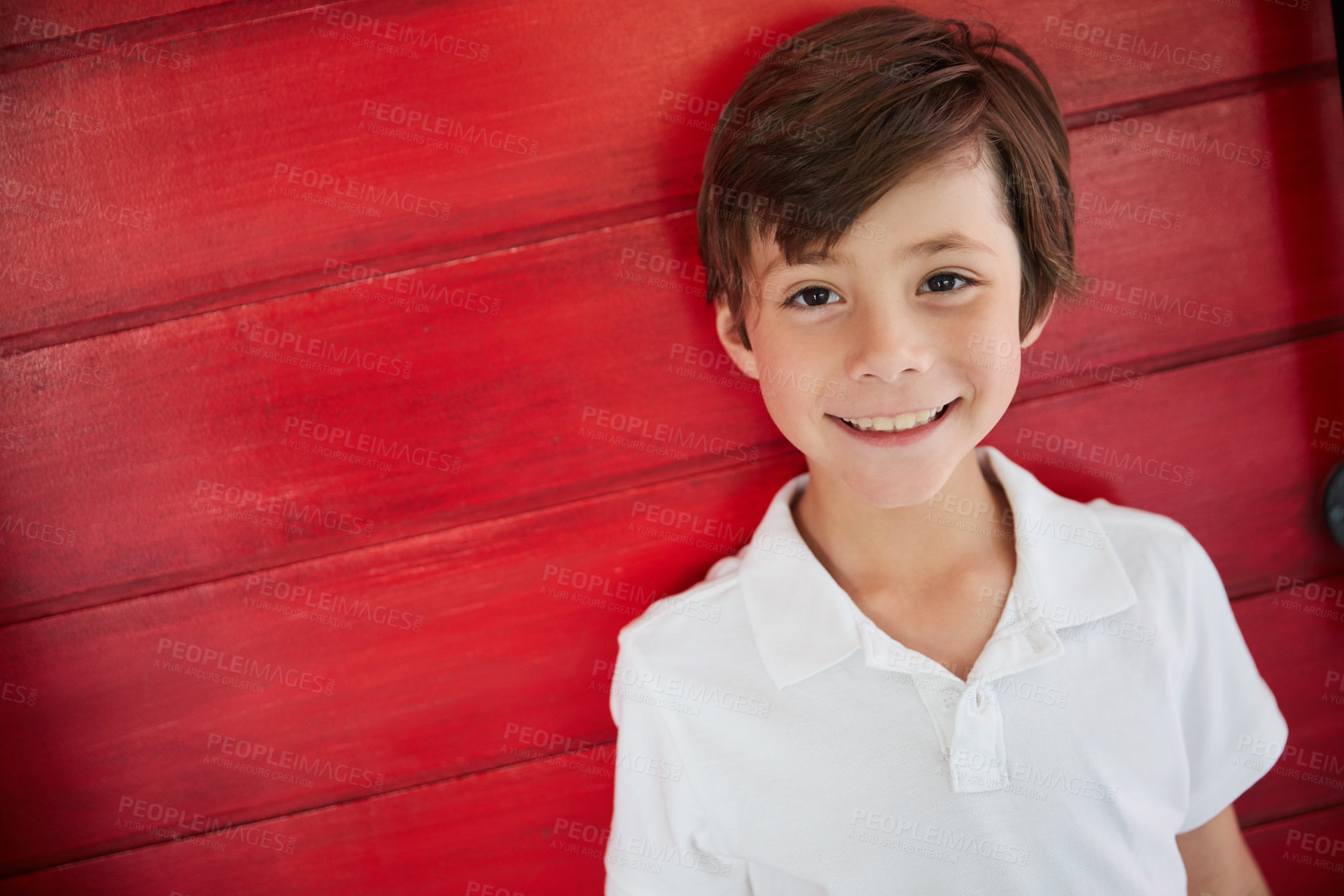 Buy stock photo Portrait of a smiling little boy standing against a red wall