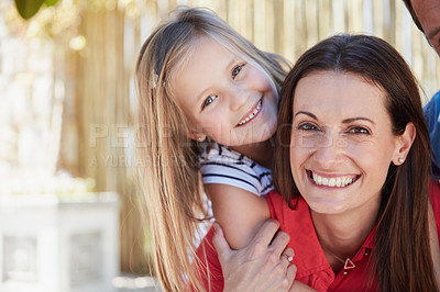 Buy stock photo Portrait of smiling mother giving her young daughter a piggyback outside in their yard on a sunny day