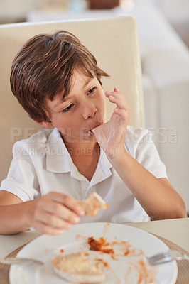 Buy stock photo Shot of a happy little boy enjoying lunch on his own at home
