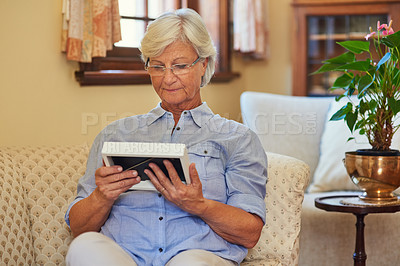 Buy stock photo Cropped shot of a senior woman looking at a photo frame at home