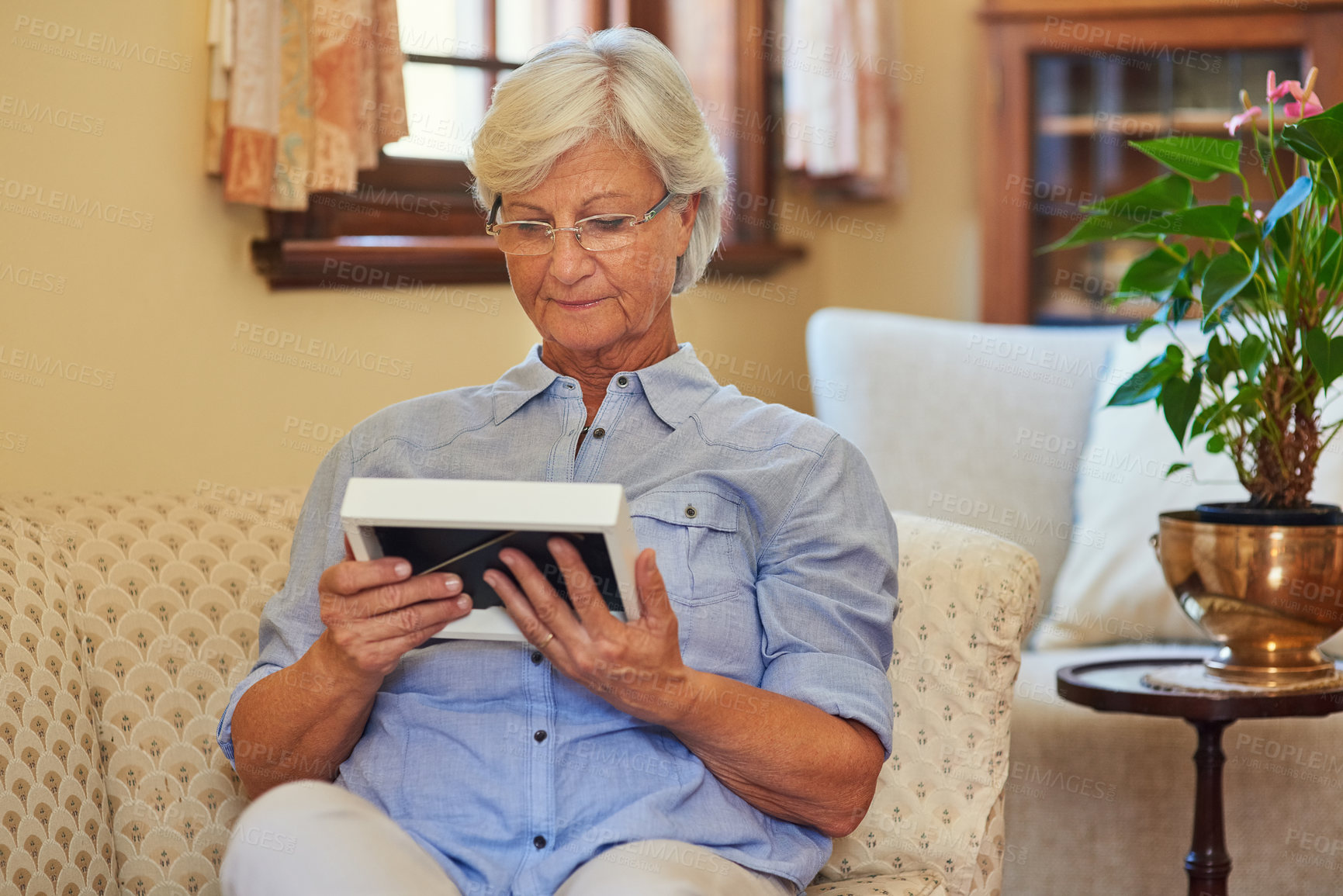 Buy stock photo Frame, senior or woman with photograph in home for memory, love or peace on living room chair. Relax, remember or lonely elderly lady looking at picture or nostalgia in retirement, lounge or house