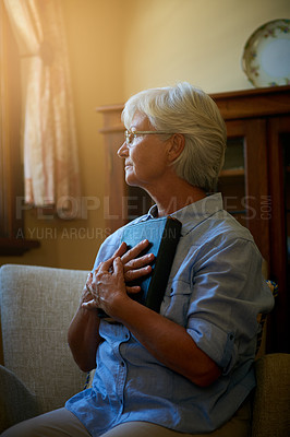 Buy stock photo Cropped shot of a senior woman holding a Bible at home