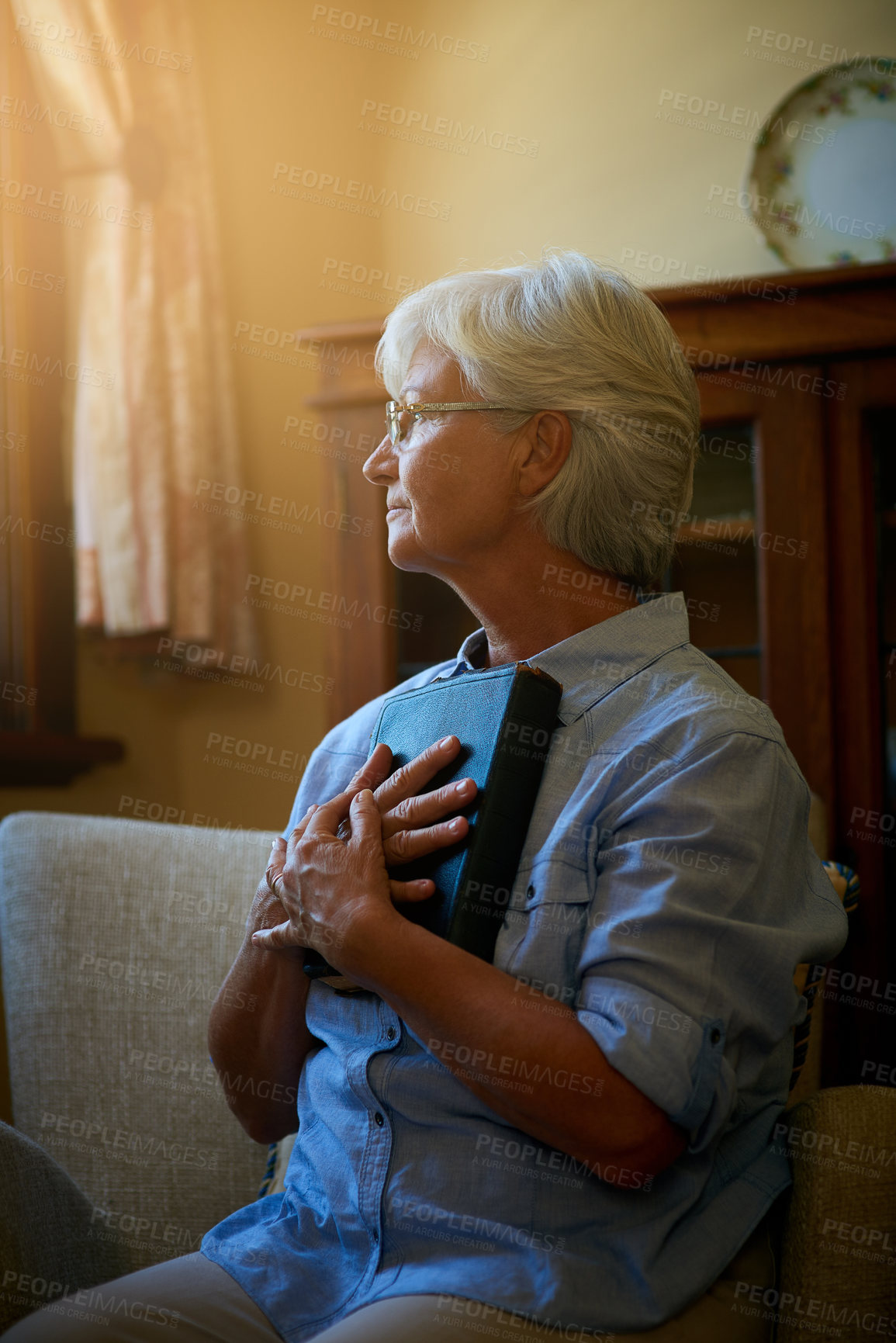 Buy stock photo Cropped shot of a senior woman holding a Bible at home