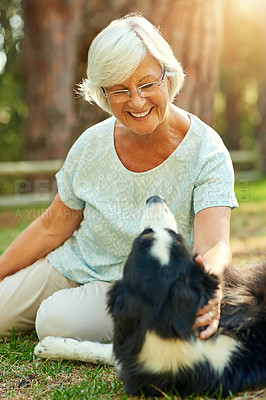 Buy stock photo Shot of a happy senior woman relaxing in a park with her dog