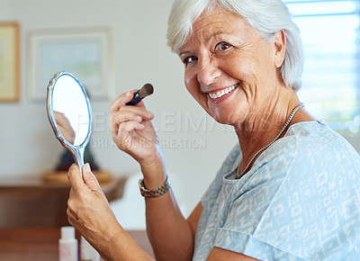 Buy stock photo Portrait of a happy senior woman using a hand mirror to apply makeup at home