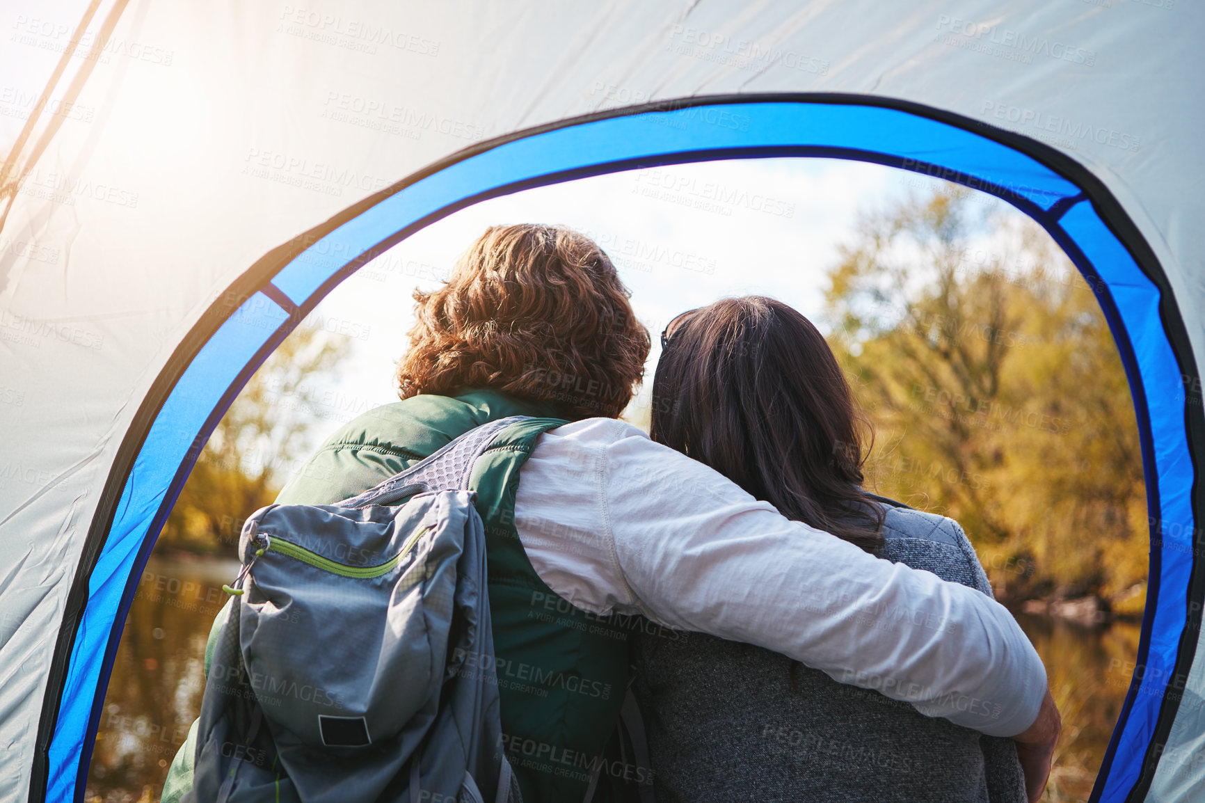 Buy stock photo Rearview shot of an affectionate young couple sitting at their campsite