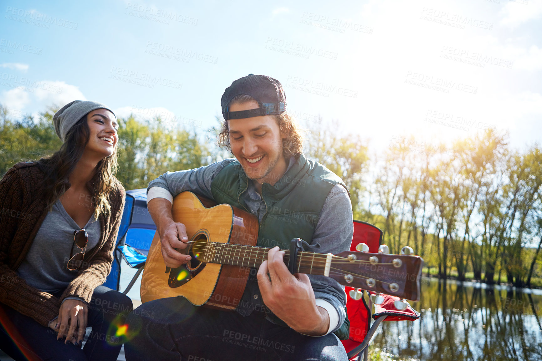 Buy stock photo Shot of a young man playing his girlfriend a song on his guitar