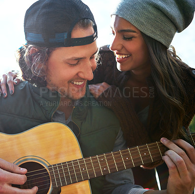 Buy stock photo Shot of a young man playing his girlfriend a song on his guitar