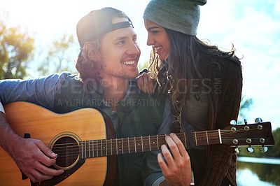 Buy stock photo Shot of a young man playing his girlfriend a song on his guitar