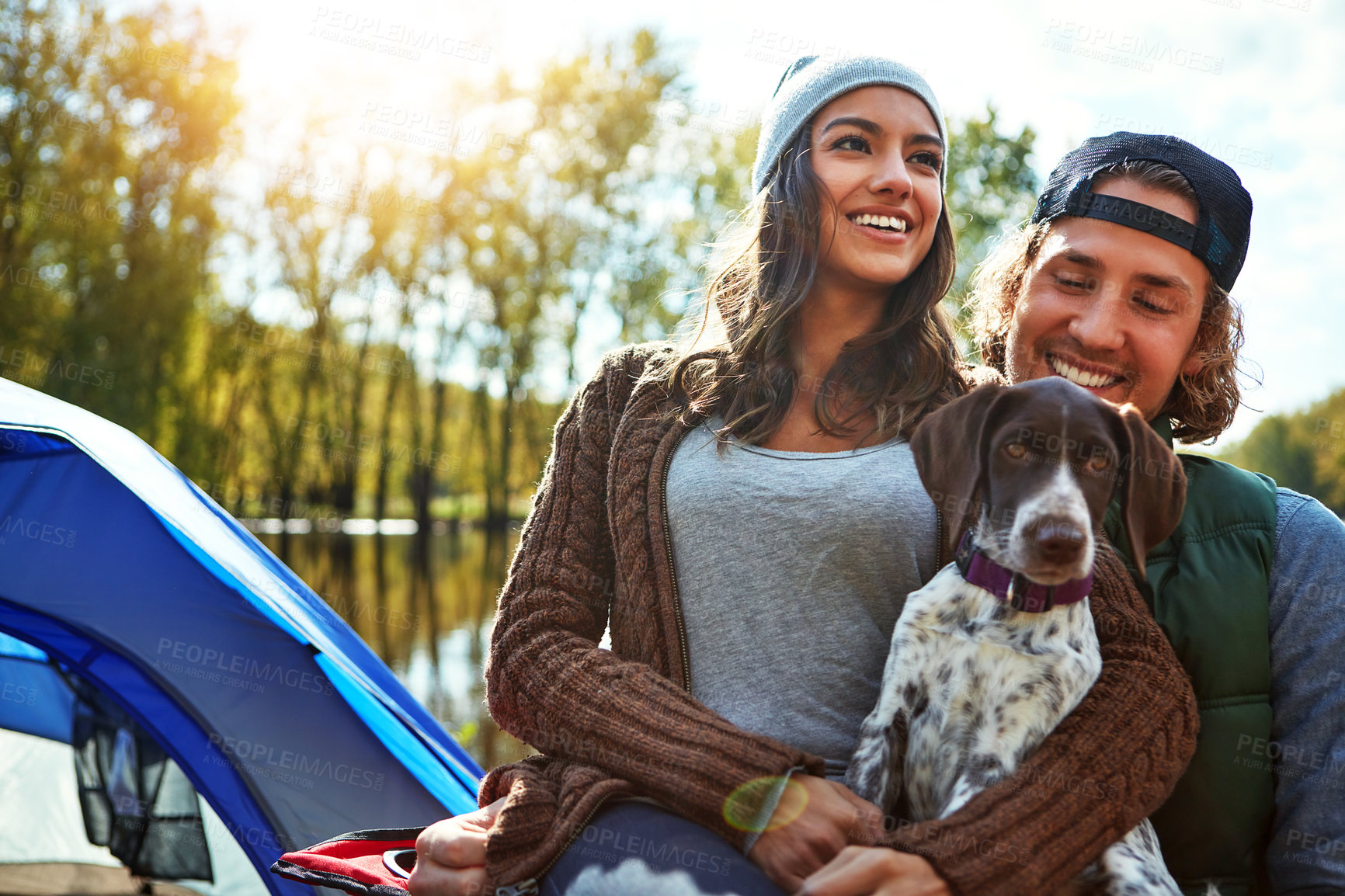 Buy stock photo Couple, camping and lake in nature with pet for freedom, adventure travel with sustainability. Man, woman and dog in countryside by water for relax on vacation, happiness for holiday environment