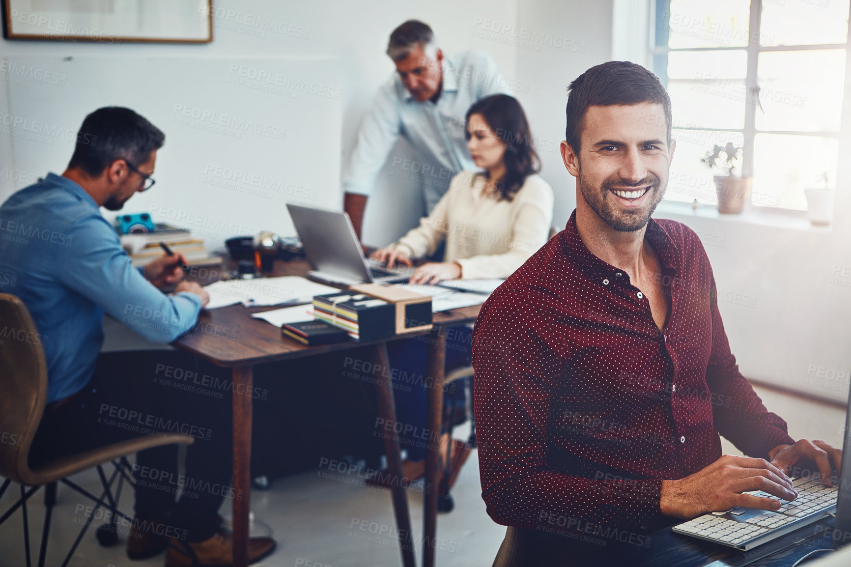 Buy stock photo Portrait of a young man working in the office with his colleagues in the background