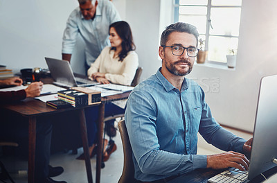 Buy stock photo Portrait of a mature man working in the office with his colleagues in the background