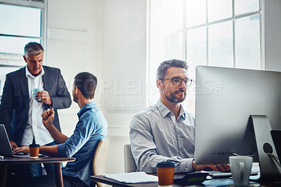 Buy stock photo Computer, work and businessman with his colleagues in the background talking, speaking and planning. Pc, success and professional male employee working on a corporate company report in the office.