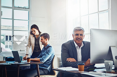 Buy stock photo Senior, portrait and business man by computer in office workplace. Pc, coworking and happy elderly male employee working on marketing report, advertising or sales project with colleagues in company.