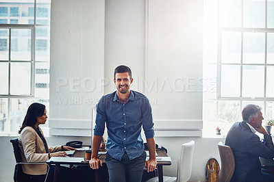 Buy stock photo Portrait of a confident young businessman managing a small team in a modern office