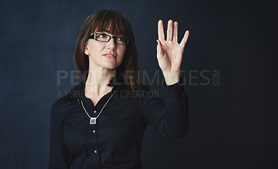 Buy stock photo Studio shot of a corporate businesswoman connecting to a user interface against a dark background