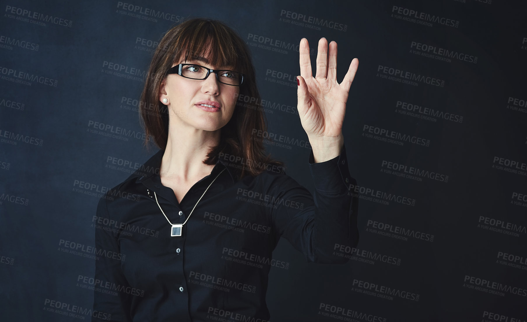 Buy stock photo Studio shot of a corporate businesswoman connecting to a user interface against a dark background
