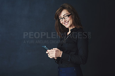 Buy stock photo Studio portrait of a corporate businesswoman texting on a cellphone against a dark background